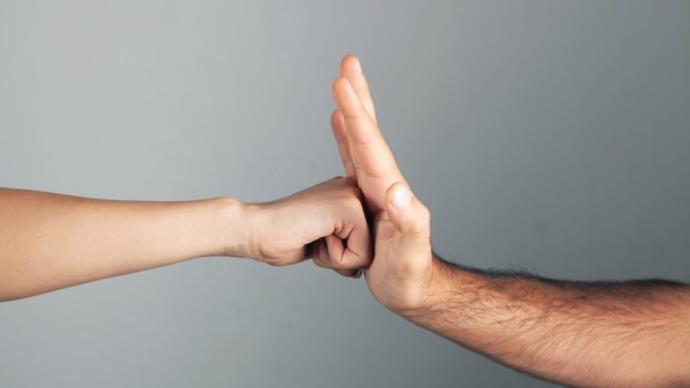 Fist hitting a palm on a gray background, representing conflict, aggression, or violence in Sri Lanka.