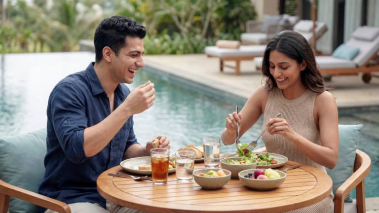 A man and woman enjoying a meal together by a pool on a sunny day, capturing a relaxed and romantic outdoor setting